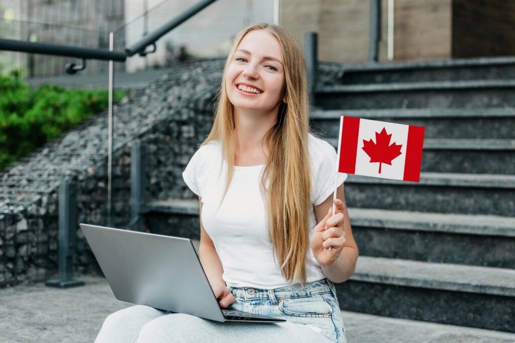 Female Student Sitting on Stairs with Laptop and Holding Small Canada Flag